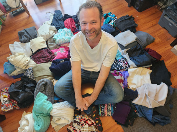 Don St Germain sitting in a pile of collected clothing before rehoming it